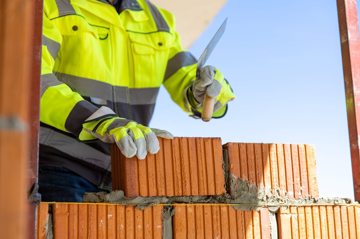 Construction worker laying brick with trowel on site during construction